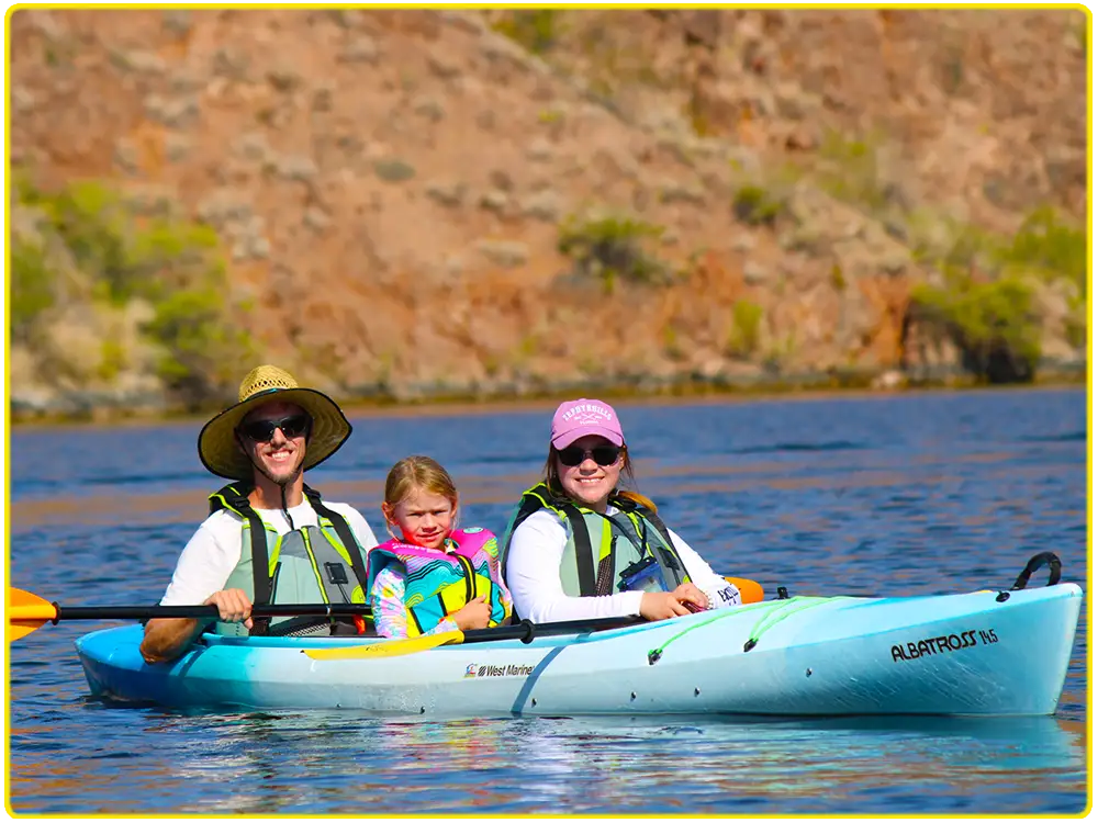 Family paddling together in a tandem kayak during a scenic guided tour on the Colorado River near Hoover Dam and Emerald Cove.