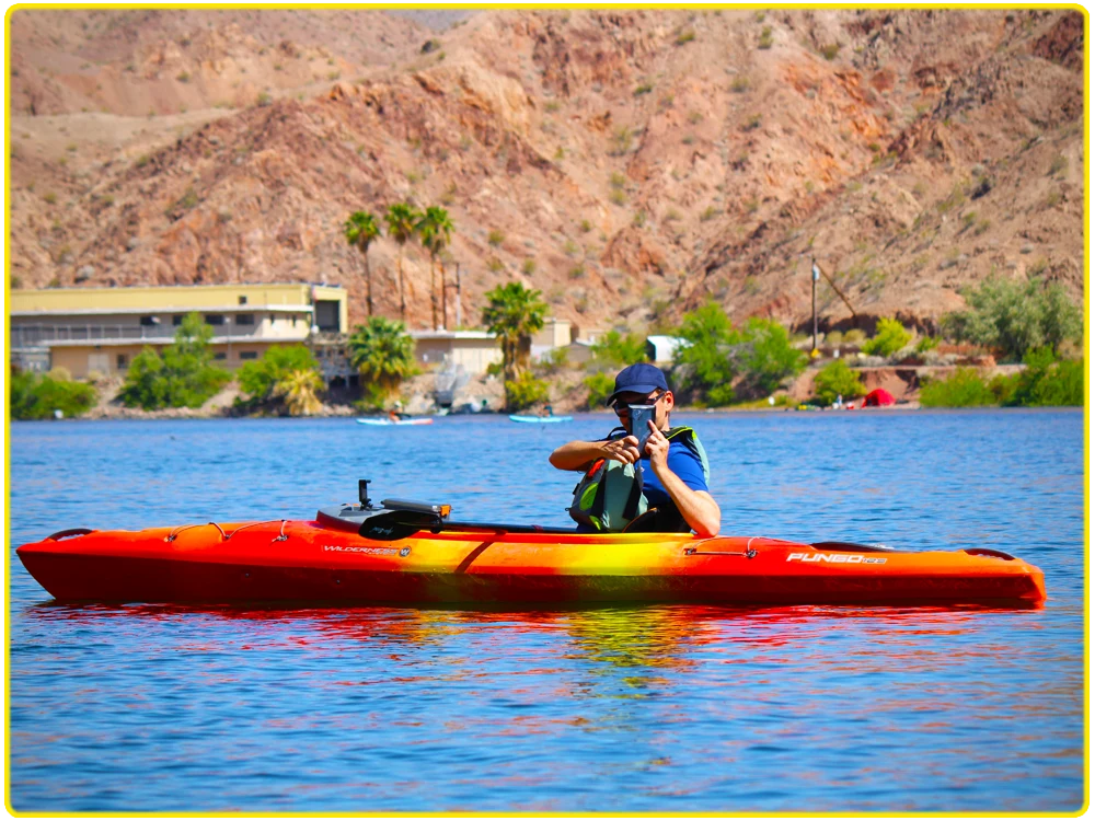 Kayaker in a red kayak on the Colorado River, capturing scenic views of rugged desert terrain, perfect for photography kayaking tours, outdoor adventure, scenic river paddling, and capturing breathtaking moments in the desert.