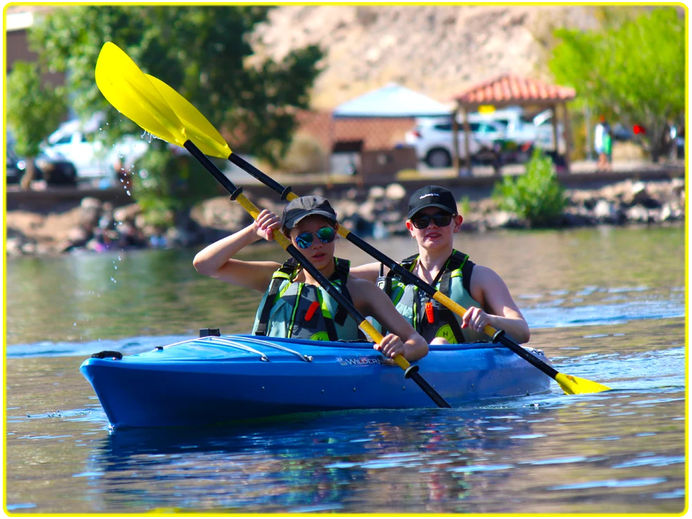 Two kayakers on the Colorado River in a bright blue tandem kayak, exploring Emerald Cove on a family-friendly, beginner kayaking tour, perfect for group kayaking adventures, scenic river paddling, and outdoor experiences.