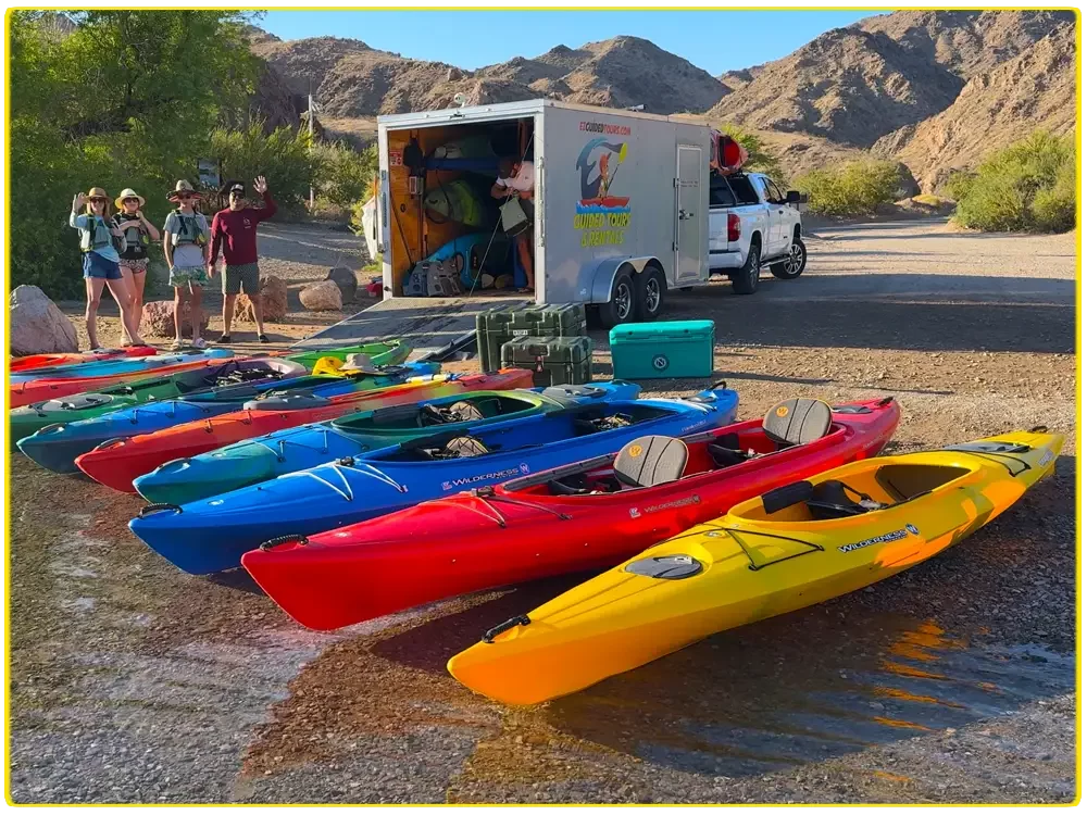 Colorful premium kayaks lined up at Willow Beach, ready for guided and self-guided kayak tours on the Colorado River, offering scenic paddling to Emerald Cove, Hoover Dam, and Black Canyon, perfect for outdoor adventures and kayaking enthusiasts.