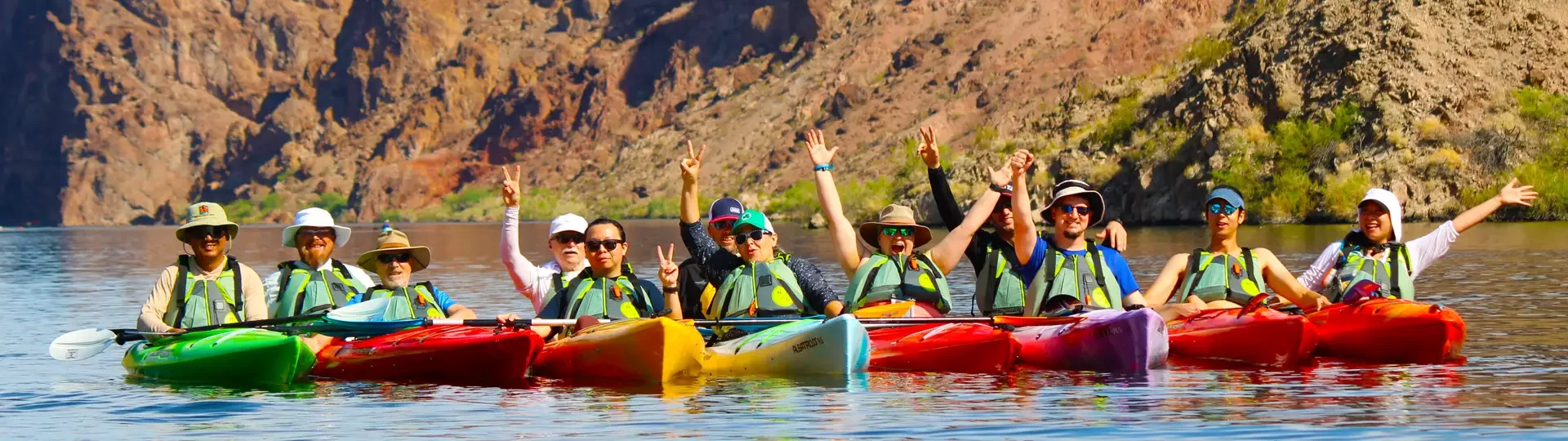 Experience the #1 Unforgettable Kayak Tours Las Vegas and Hoover Dam on the Colorado River, just minutes from the Strip. Paddle through breathtaking canyons, visit the Emerald Cave, and enjoy one of Las Vegas’s top outdoor activities. Recognized by TripAdvisor, Viator, and Google’s “Top Things to Do,” our tours offer fun and excitement for all ages. Now Booking for 2025 - tours and rentals available year-round! A large group of kayakers raising paddles in celebration during a guided kayaking tour along the Colorado River, with scenic views of Emerald Cove and Black Canyon.